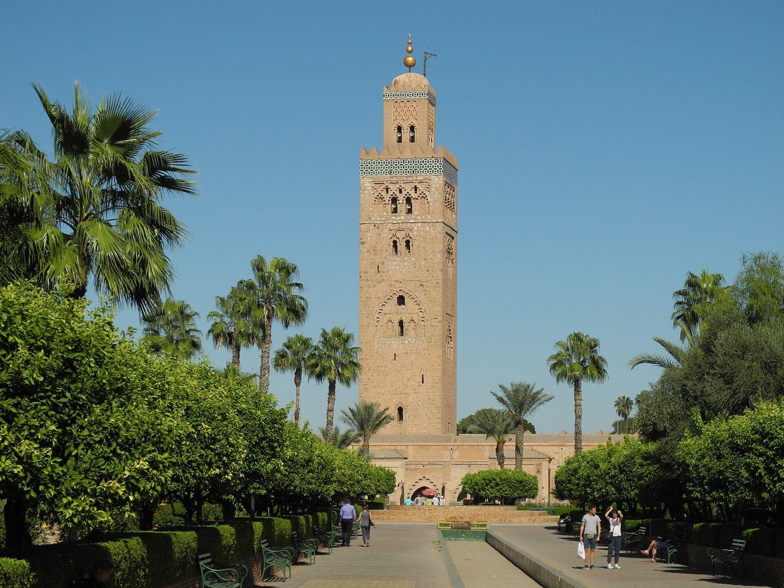 The Koutoubia minaret rising above palm trees and gardens under a blue sky in Marrakech