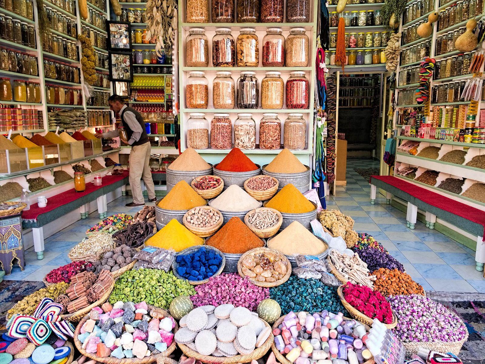 Spice shop in a Moroccan souk with cones of colourful spices, baskets of dried flowers and jars on shelves