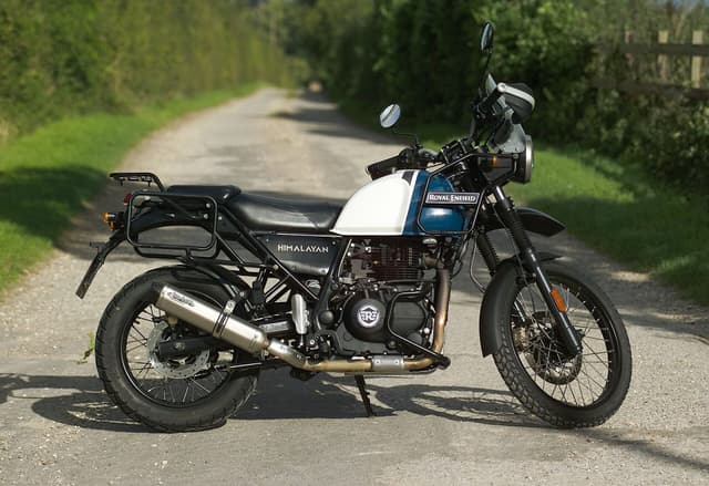 Blue and white Royal Enfield Himalayan adventure motorcycle parked on a quiet country lane