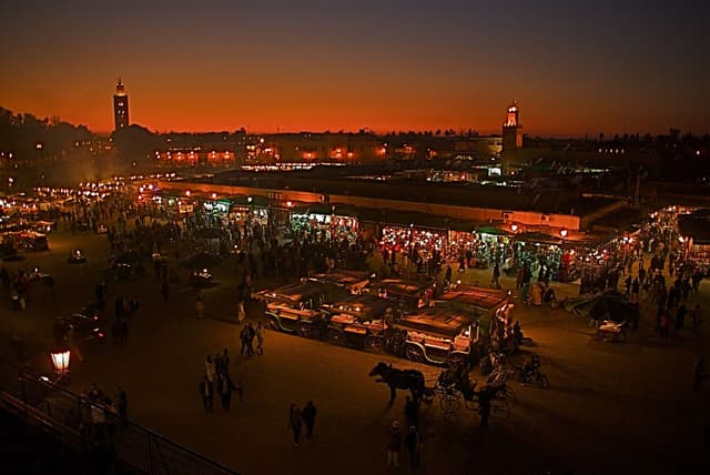 Jemaa el-Fna square in Marrakech at dusk with food stalls lighting up and smoke rising