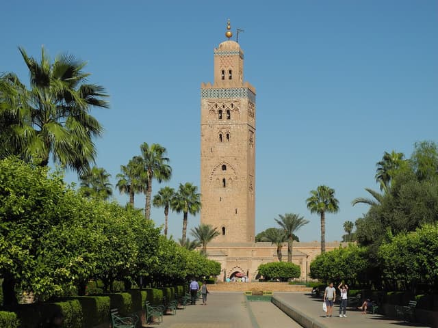 The Koutoubia minaret rising above palm trees and gardens under a blue sky in Marrakech